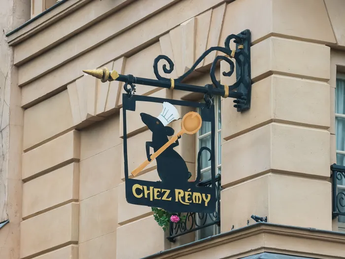 Enseigne en fer forgé du Bistrot Chez Rémy montrant Rémy le rat chef brandissant une louche, façade du restaurant
