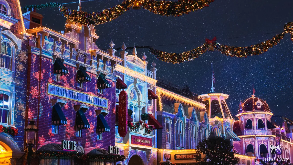 The facades of Main Street U.S.A. lit with bluish Christmas projections and fairy lights at night at Disneyland Paris