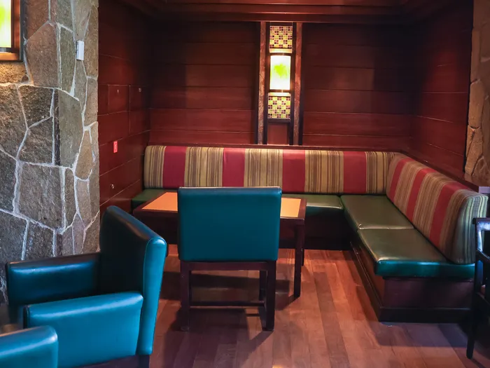 Alcôve du Redwood Bar au Sequoia Lodge, banquette rayée, fauteuils bleus et murs en pierre et bois sombre