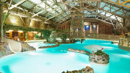 La piscine intérieure du Disney Davy Crockett Ranch, sous une grande charpente en bois avec cascade et toboggan
