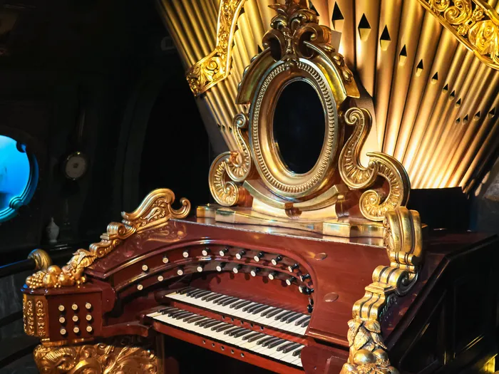 Orgue en bois et dorures face à un hublot du sous-marin, dans Les Mystères du Nautilus à Discoveryland.