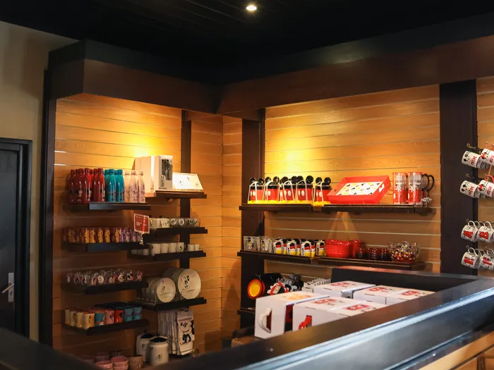 Shelf of red Mickey mugs and cups lined up on wooden shelves at Disneyland Paris.