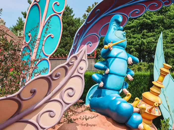 Statue de la Chenille bleue fumant sa pipe parmi des feuilles géantes dans Alice’s Curious Labyrinth