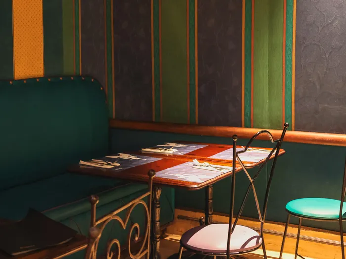 Banquette verte et table dressée devant des murs à rayures colorées de l’Agrabah Café