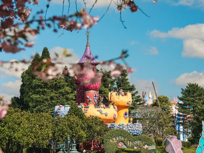 Le château de la Reine de Cœur du Labyrinthe d’Alice à Fantasyland, encadré de cerisiers en fleurs.