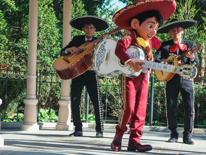 Miguel plays his white guitar in front of two mariachis in sombreros during Miguel’s Fiesta Latina at Disneyland Paris
