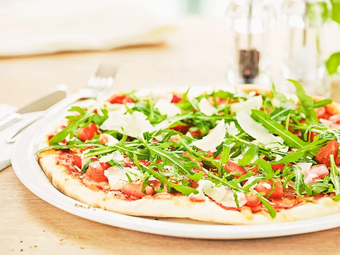 Pizza fine garnie de tomates, roquette et copeaux de parmesan servie au Vapiano du Disney Village.