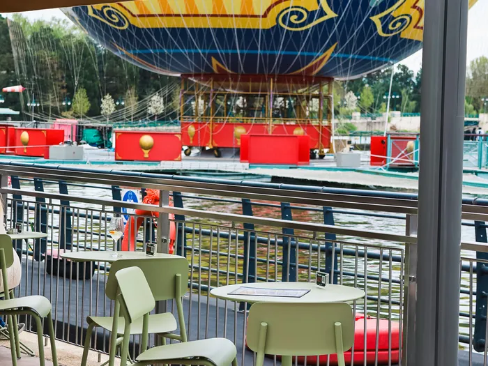 Terrasse aux chaises vertes sous un parasol Petite Rosalie face au lac