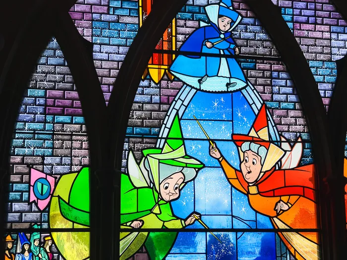 Vitrail coloré représentant les trois bonnes fées, dans la Galerie de la Belle au Bois Dormant à Fantasyland.