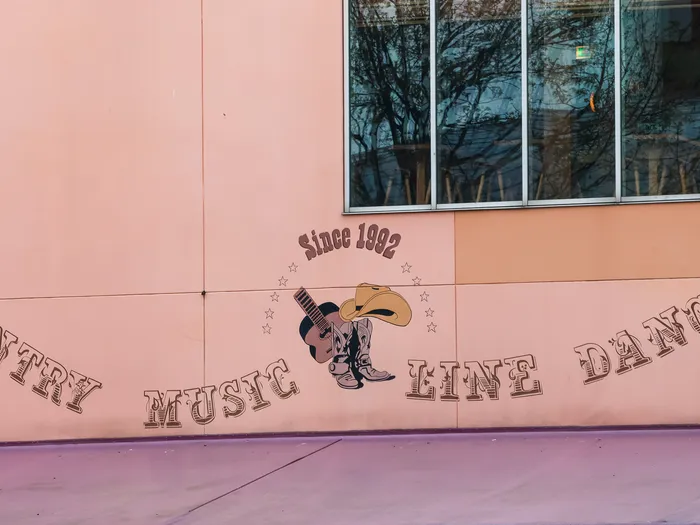 Mur rose du Billy Bob’s orné de la fresque « Country Music Line Dancing » avec guitare et bottes