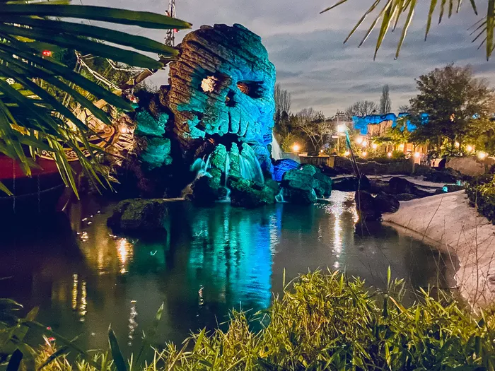 Skull Rock illuminé en bleu au crépuscule, au bord de la rivière d’Adventure Isle, à Adventureland.