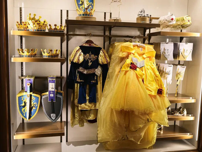 Costume de prince bleu et or près d’une robe jaune de Belle chez Mon Rêve Royal