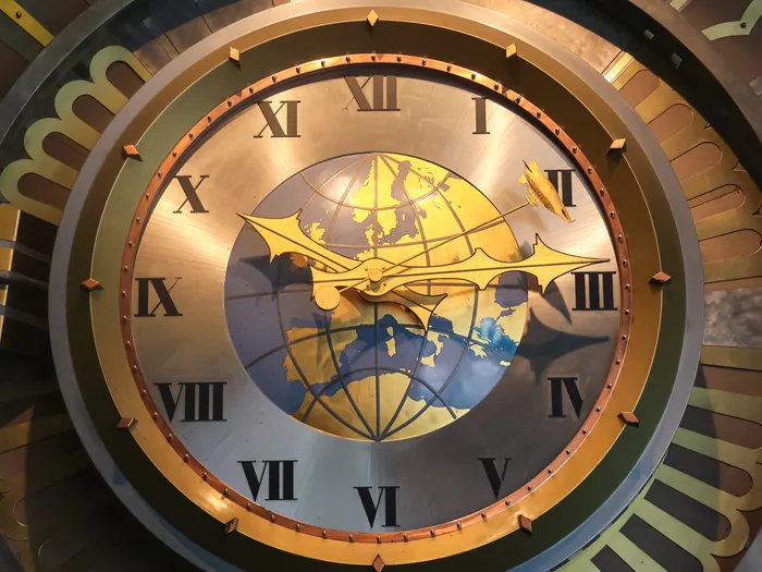 Grande horloge dorée à chiffres romains ornée d’un globe terrestre, au Café Hyperion à Discoveryland.