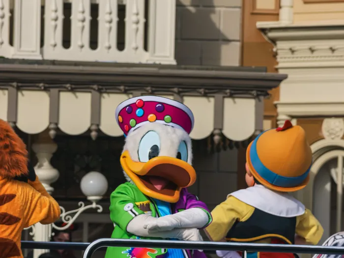 Donald et Pinocchio en costumes colorés sur un char de la parade A Million Splashes of Colour, façades de Main Street