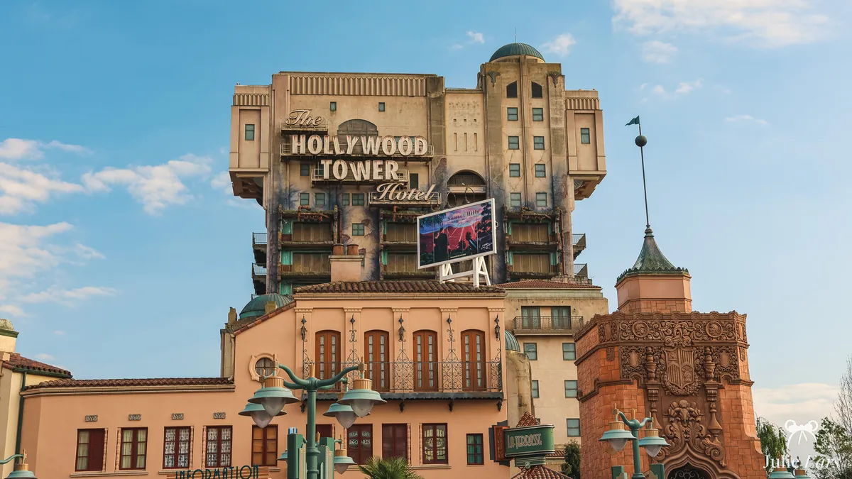 The Hollywood Tower Hotel (The Twilight Zone Tower of Terror) and its sign rise above salmon-pink frontages and green lampposts at Disneyland Paris
