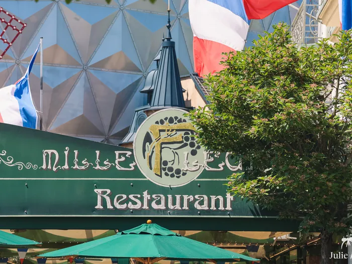 Enseigne verte du restaurant Mille Fleurs, drapeaux français et dôme en arrière-plan, à Europa-Park