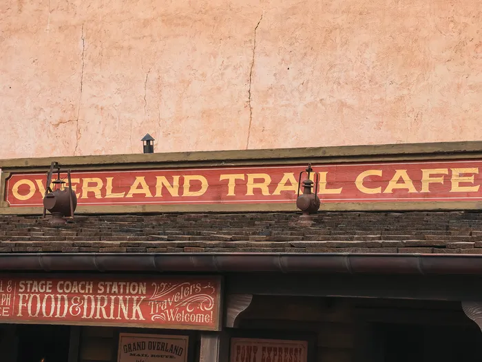 L'enseigne rouge « Overland Trail Cafe » et ses affiches de station de diligence, à Frontierland.