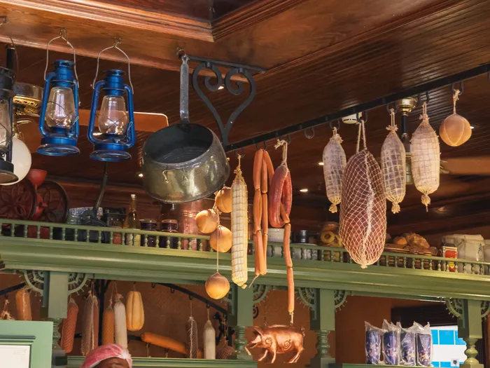 Saucissons et lanternes bleues suspendus au plafond en bois du Market House Deli, décor d’épicerie ancienne