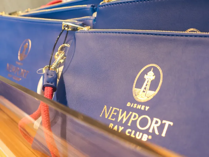 Blue pouches with the gold Disney Newport Bay Club logo and a red rope wrist strap.