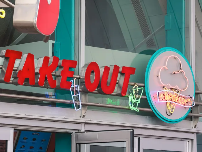 Enseigne Take Out en lettres rouges et néons colorés au-dessus du comptoir à emporter d’Annette’s Diner.
