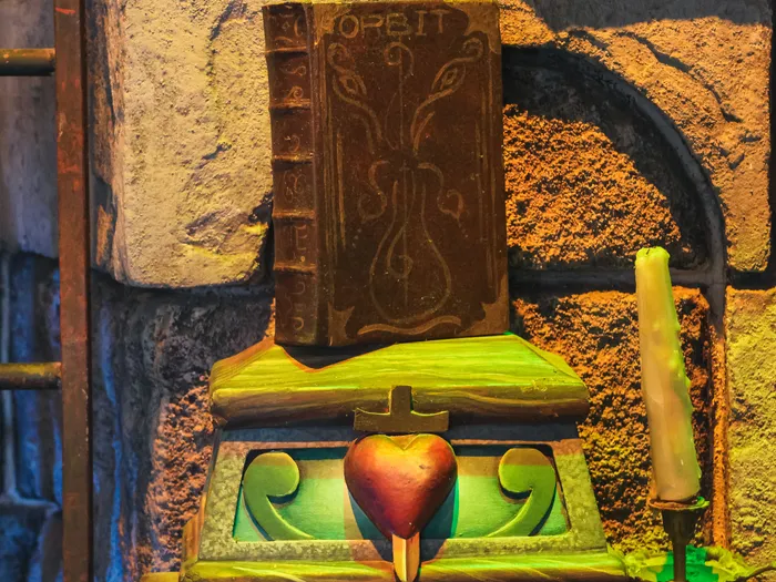 Décor sombre avec un vieux grimoire et un coffret orné d’un cœur éclairés dans l’attraction Blanche-Neige