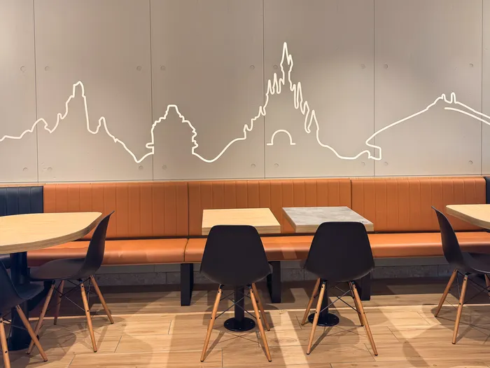Salle du McDonald’s de Disney Village, banquette orange et fresque murale au trait figurant le château Disney.