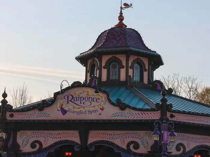Toit coloré et enseigne du manège Raiponce Tangled Spin sous un ciel bleu, au Parc Disney Adventure World.
