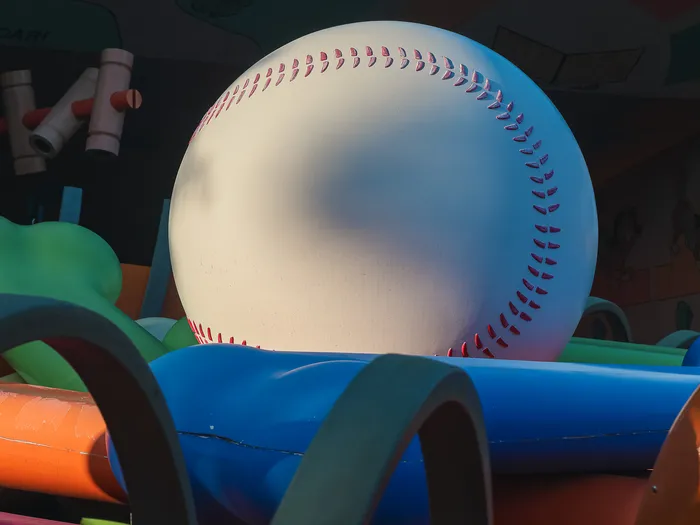 Balle de baseball géante posée sur des tubes colorés, décor de l’attraction Slinky Dog Zigzag Spin à Toy Story Playland