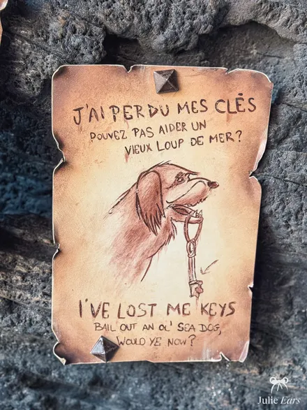 Scroll nailed to the rock on Adventure Isle at Disneyland Paris: a drawn dog holding a key, titled "I’ve lost my keys"