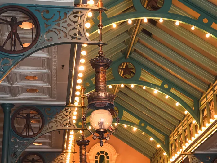 Charpente verte et dorée de la Discovery Arcade, guirlandes lumineuses et lustre suspendu sur Main Street