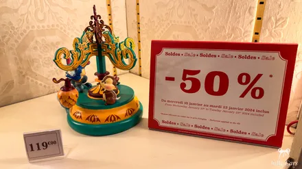 A Disney collectible in a shop next to a red 50% off sign, during the winter sales at Disneyland Paris.