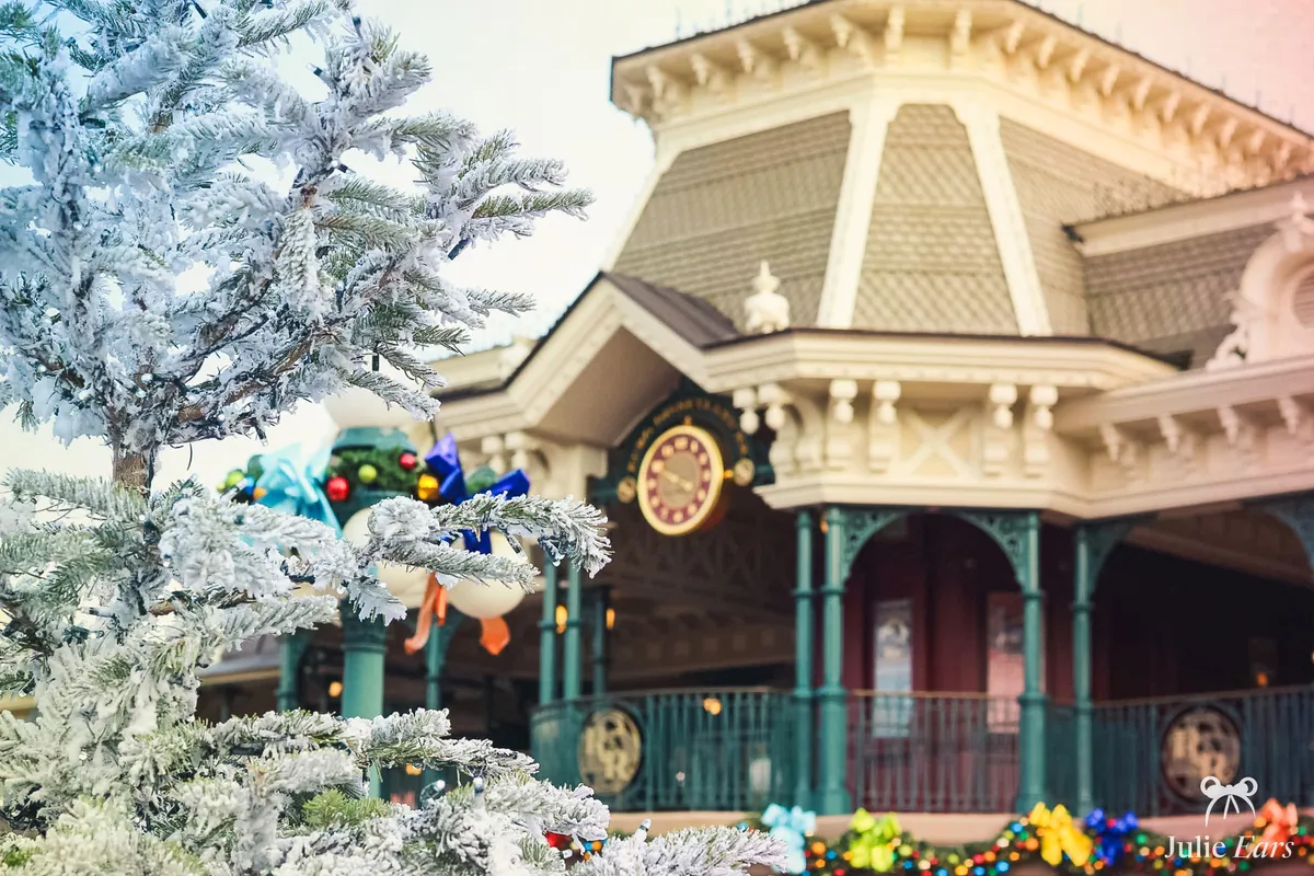 Gare de Main Street décorée pour Noël avec un sapin enneigé à Disneyland Paris