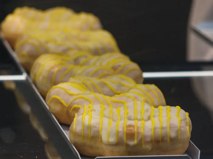 Rangée de donuts à glaçage blanc strié de jaune, présentés en vitrine au kiosque Searchlight.