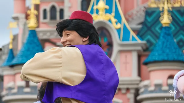 Aladdin, gilet violet et tarbouche rouge, devant le château à Disneyland Paris.