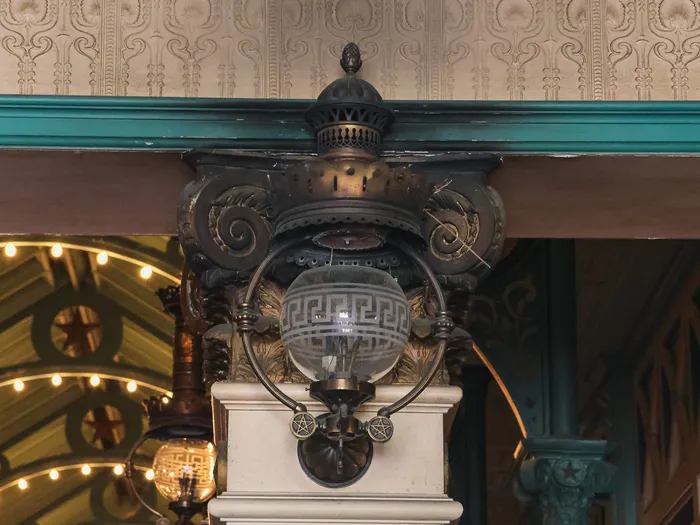 Lanterne ancienne à globe de verre fixée sous une corniche ouvragée dans la galerie Liberty Arcade.