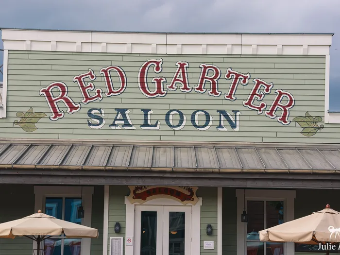 Enseigne peinte Red Garter Saloon sur la façade vert d’eau du restaurant de l’hôtel Cheyenne, parasols en dessous