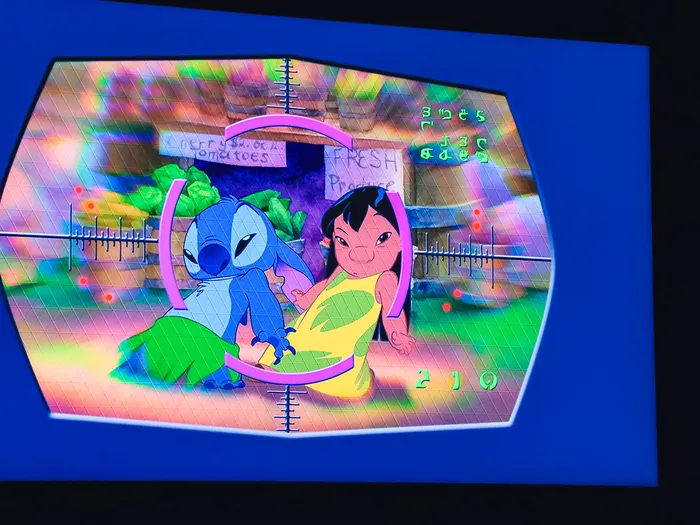 Écran de Stitch Live montrant Stitch et Lilo dans un viseur violet devant un étal de légumes coloré.