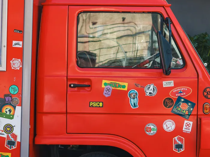 Red cab of the FAN-tastic Food Truck at Disneyland Paris, covered in Avengers and Stark stickers, with the menu displayed on the left