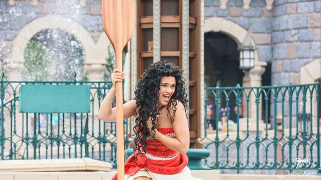 La princesse Vaiana, tenue rouge et rame à la main, rit lors de la parade à Disneyland Paris.