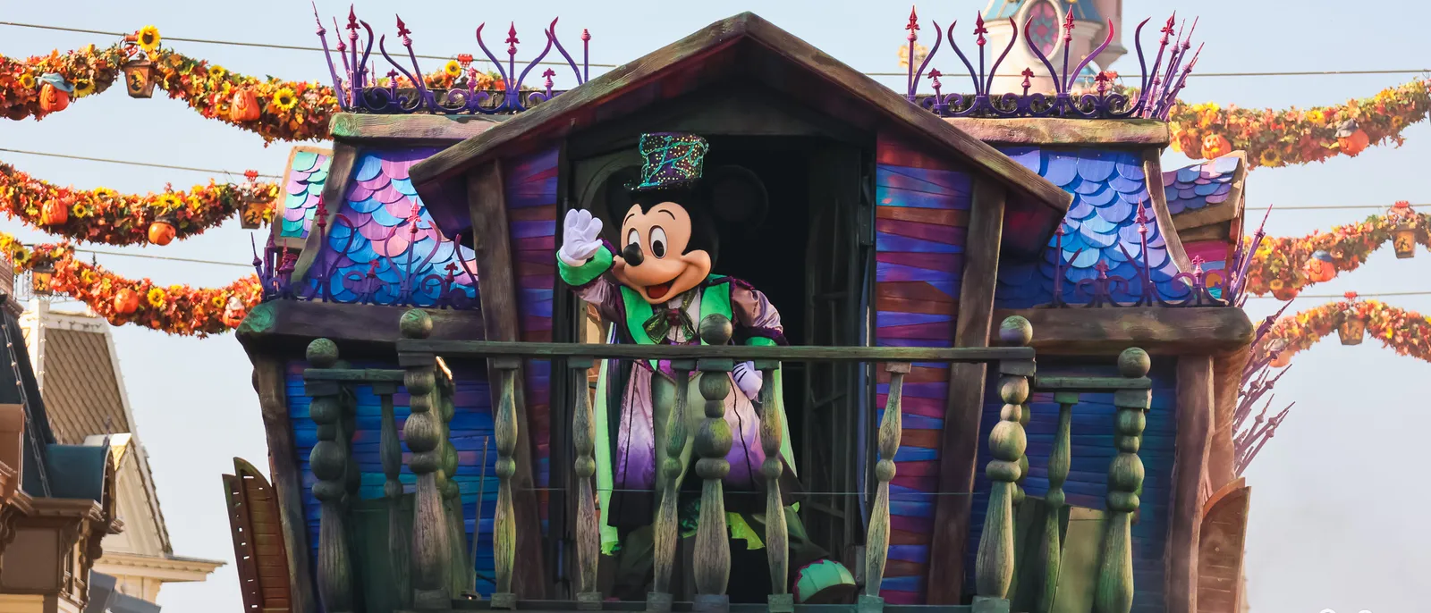 Mickey en costume et haut-de-forme salue depuis un char d’Halloween en forme de maison hantée, Main Street.