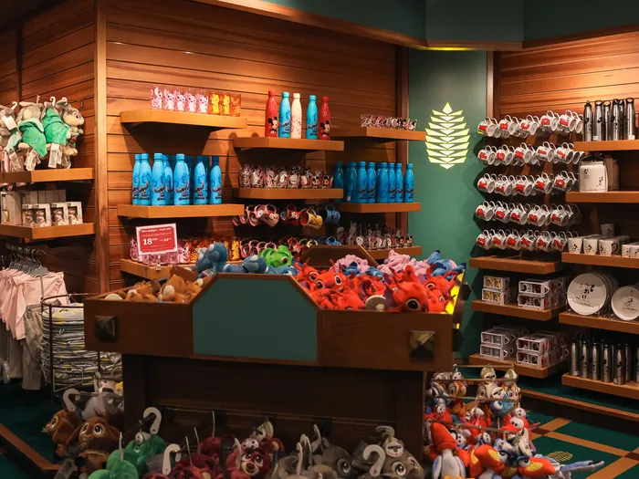Shelves of clothing, blue water bottles and mugs, with a bin of soft toys in the centre