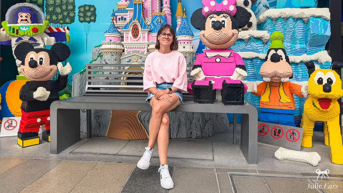 Giant LEGO sculptures of Mickey, Minnie, Goofy, Pluto, Buzz and the castle outside the LEGO Store in Disney Village, with a bench for photos
