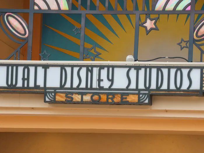 Enseigne Art déco lumineuse "Walt Disney Studios Store" sous un décor de vitrail coloré