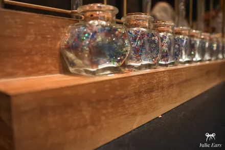 Petits flacons de gemmes colorées à choisir pour décorer sa baguette magique, à Disneyland Paris.