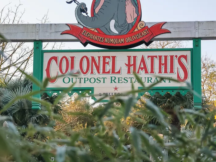 Enseigne du Colonel Hathi’s Outpost Restaurant avec logo d’éléphant, surplombant la végétation à Adventureland.