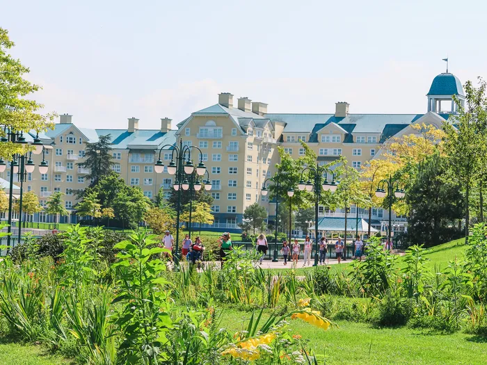 Façade jaune aux toits bleus du Newport Bay Club vue depuis les jardins fleuris bordant le lac Disney