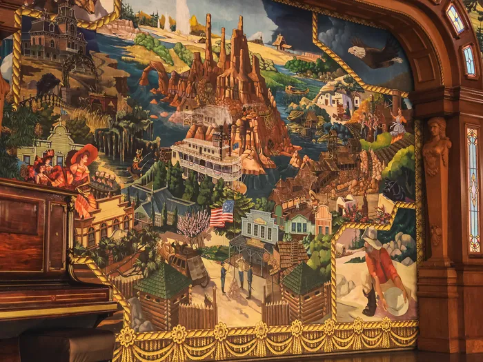 Fresque peinte d’un paysage de l’Ouest américain sur un mur boisé du Lucky Nugget Saloon, restaurant de Frontierland.