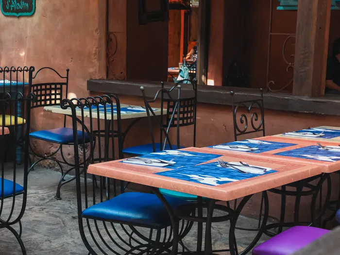 Tables aux sets bleus décorés de poissons et chaises en fer forgé dans la salle de l’Agrabah Café