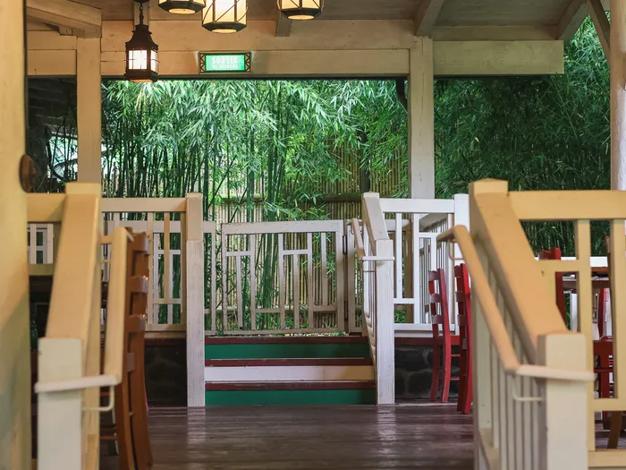 Salle couverte aux balustrades de bois du Colonel Hathi’s ouverte sur des bambous, à Adventureland.