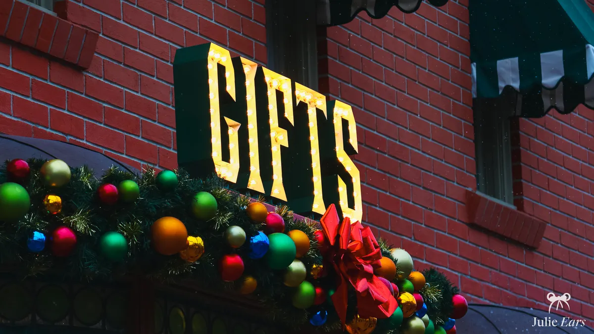 Enseigne lumineuse Gifts d’une boutique de Main Street décorée d’une guirlande de Noël et de boules colorées à Disneyland Paris
